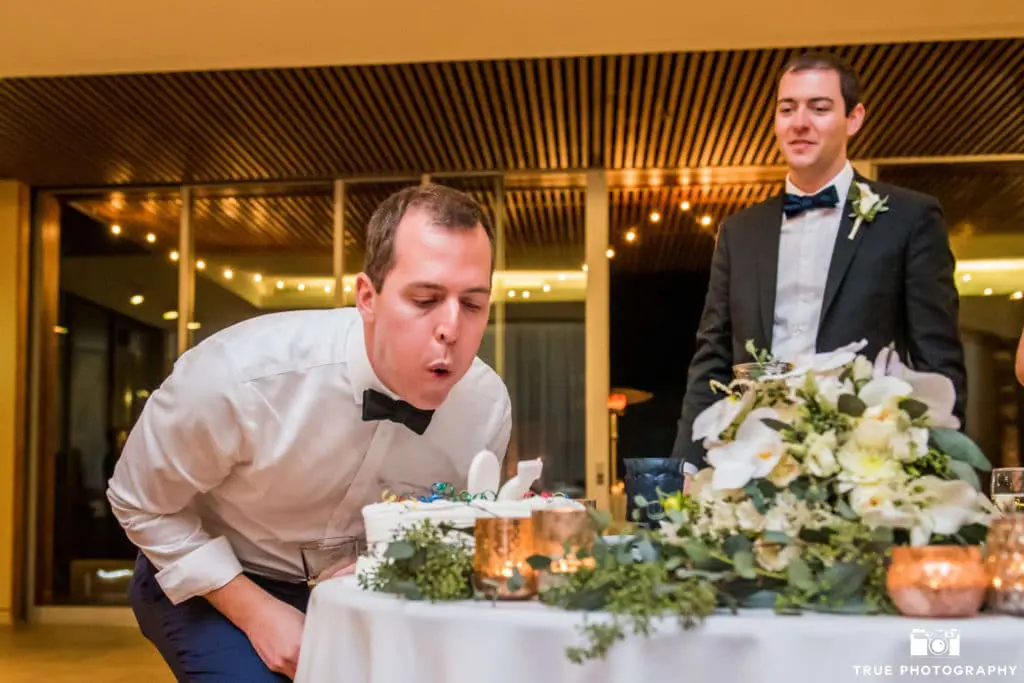 Here, the groom's brother blows out the candles on his surprise birthday cake from the bride and groom.