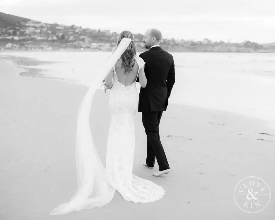 The bride and groom walk along the beach at La Jolla Shores