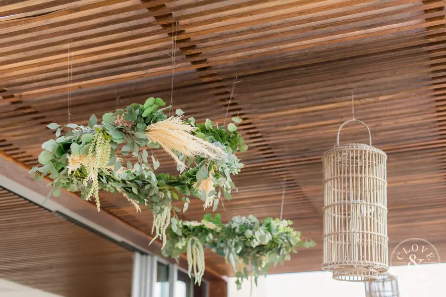 Floral wreathes and wicker lanterns hang from the slated patio covering.