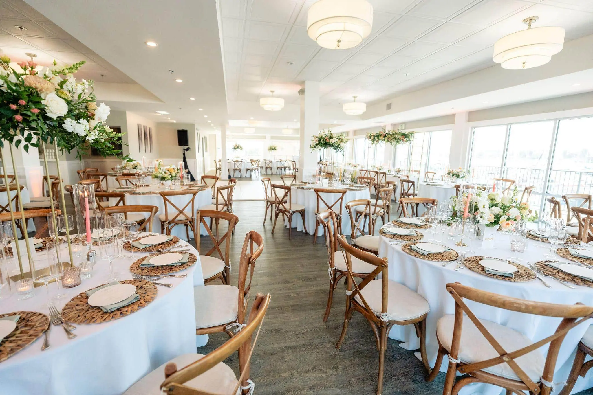 Beautifully decorated wedding reception hall with white table linens, floral centerpieces, and soft lighting