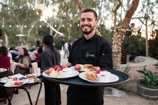 Personal Touch Dining team member carrying a variety of plates depicting full-service catering.