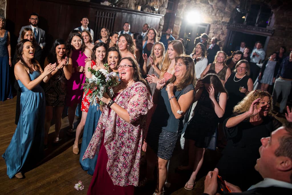 Wedding guests gathered on the dance floor for the garter and bouquet toss