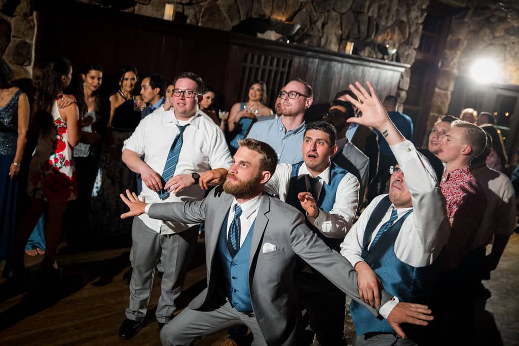Groom performing the garter removal during a wedding reception toss tradition