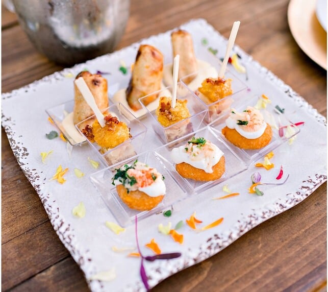 Assorted gourmet appetizers on a decorative tray, garnished with colorful herbs and spices