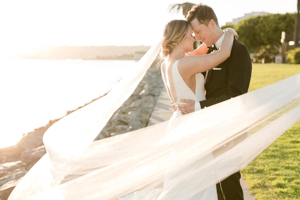 Waterfront San Diego wedding at sunset, couple embracing with flowing veil, Personal Touch Dining wedding caterers